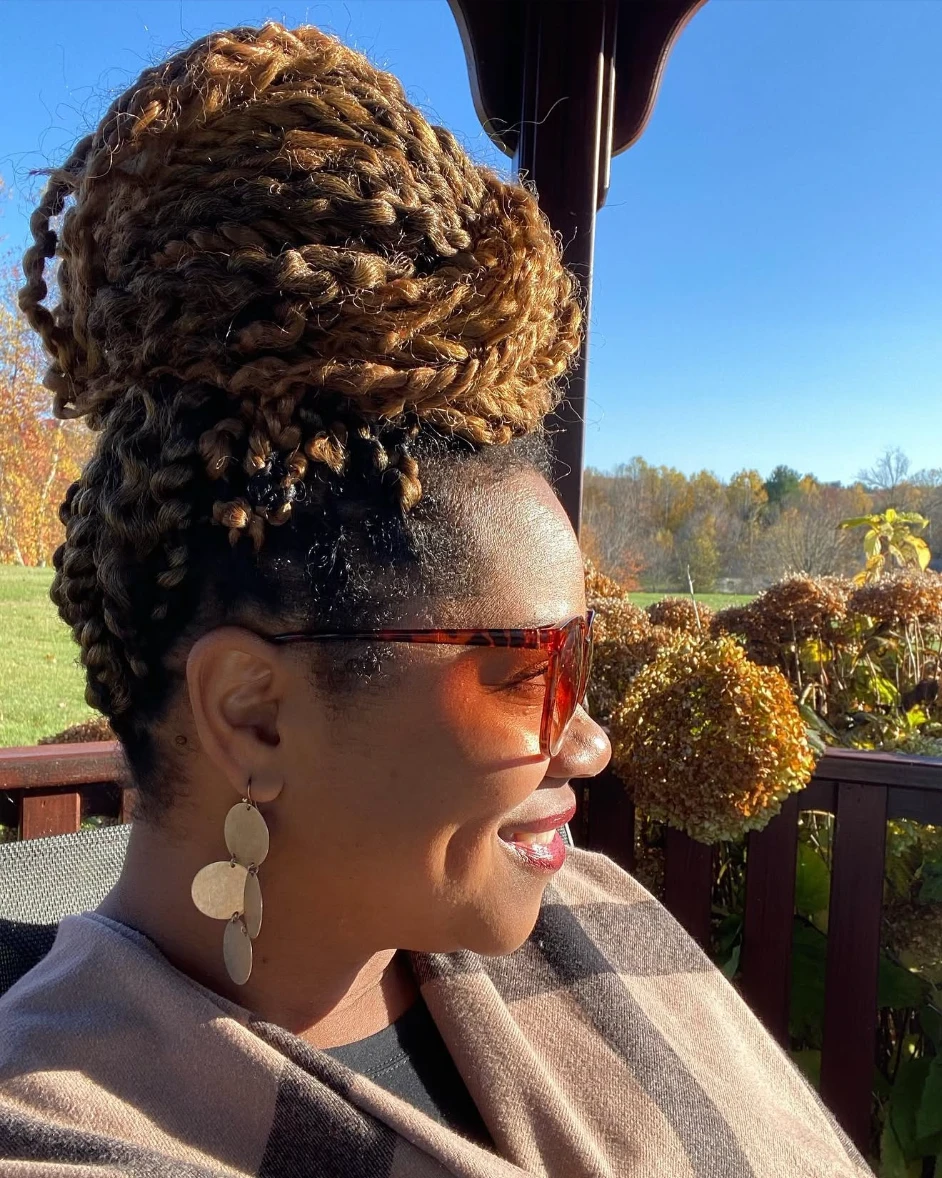 Shay wearing a high braided bun and sunglasses outdoors