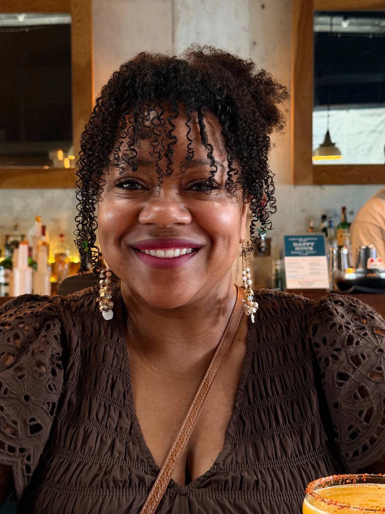 Shay smiling with natural curls at a restaurant